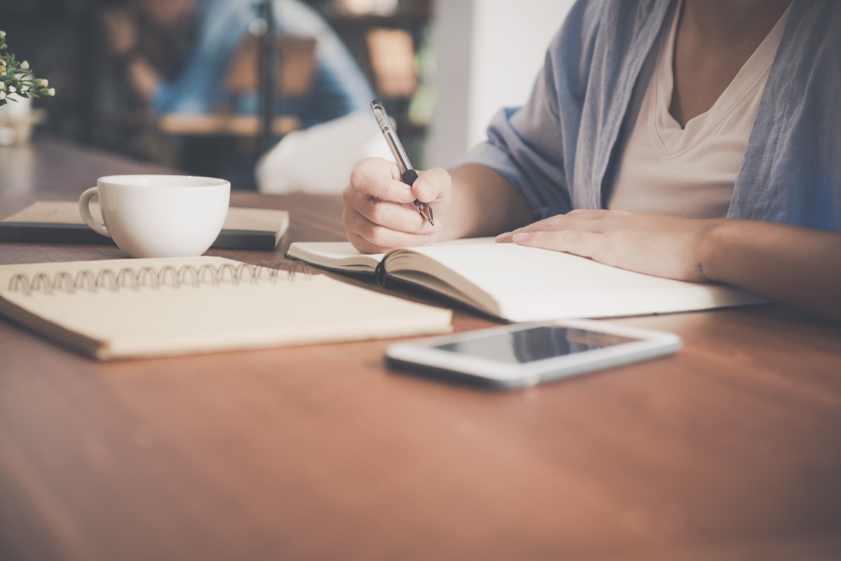 Person taking notes at a desk while routine work is handled elsewhere